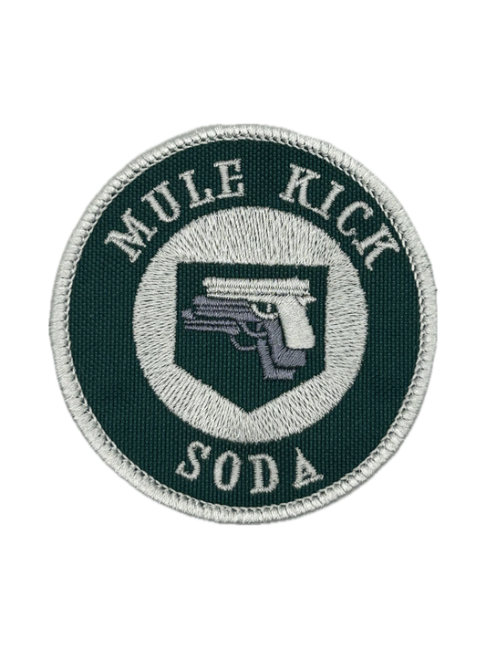 Circular patch with 'Mule Kick Soda' text and gun emblem on a white background