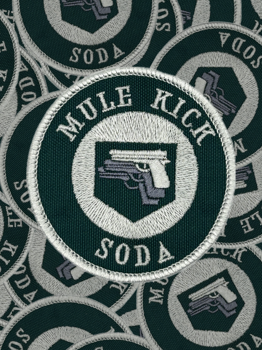 Circular patch with 'Mule Kick Soda' text and logo on a green background, surrounded by similar patches.