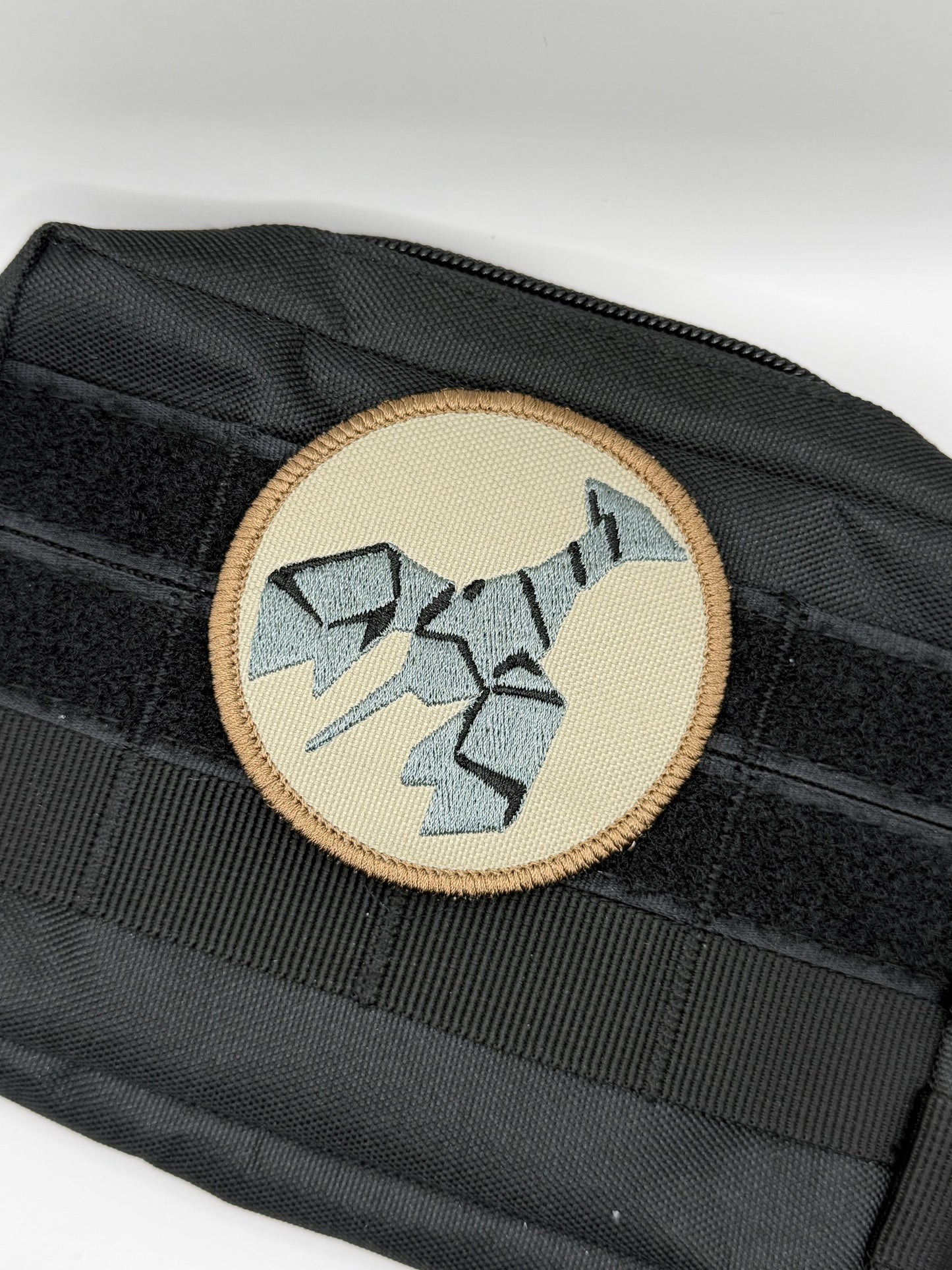 Black tactical pouch with a round patch featuring a geometric burnt lobster design on a white background