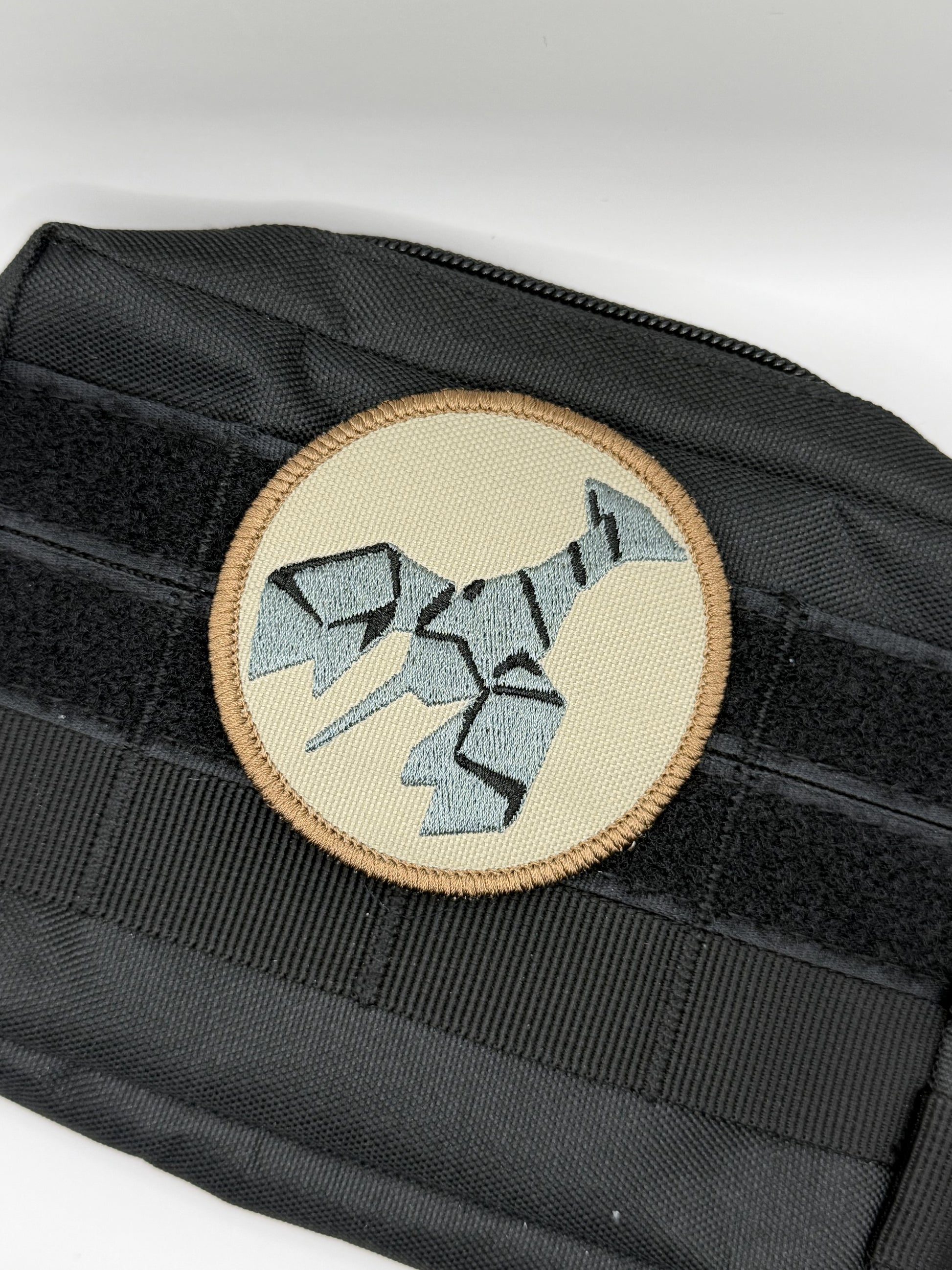 Black tactical pouch with a round patch featuring a geometric burnt lobster design on a white background