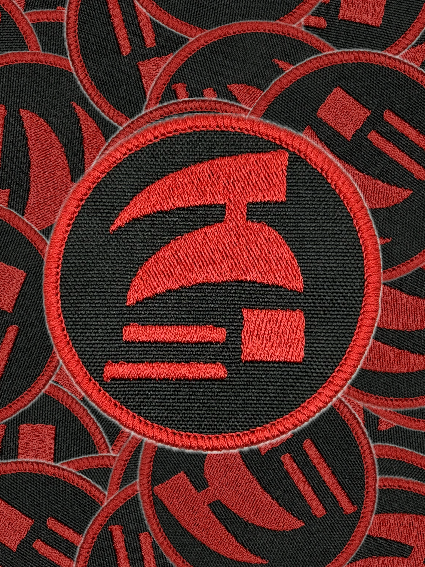 Red and black embroidered patch with a logo on a black background. Red and black circular patch with a logo on a white background. Hardcore ironman logo patch.