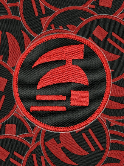 Red and black embroidered patch with a logo on a black background. Red and black circular patch with a logo on a white background. Hardcore ironman logo patch.