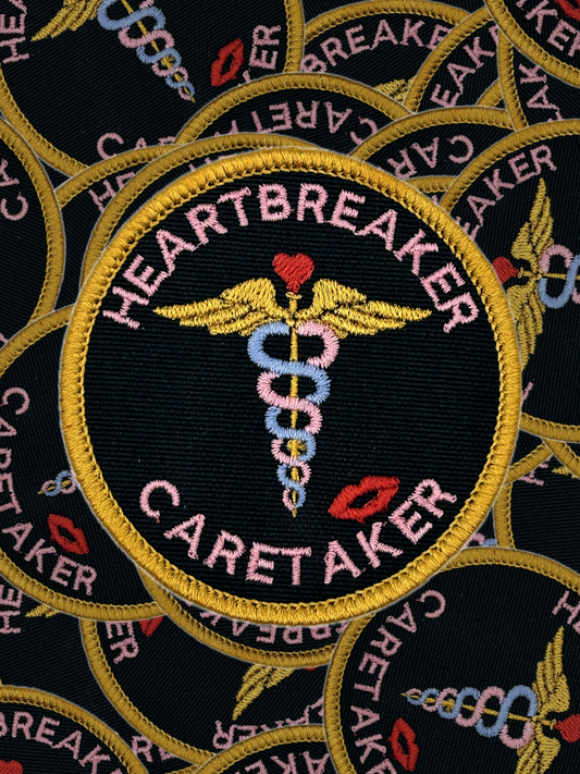 Embroidered patch with 'Heartbreaker Caretaker' design on a black background