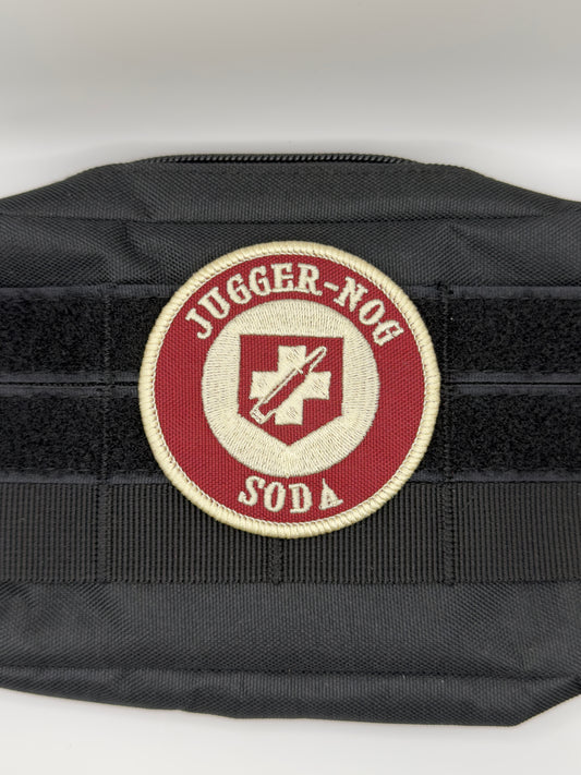 Black tactical vest with a red and white patch on a white background