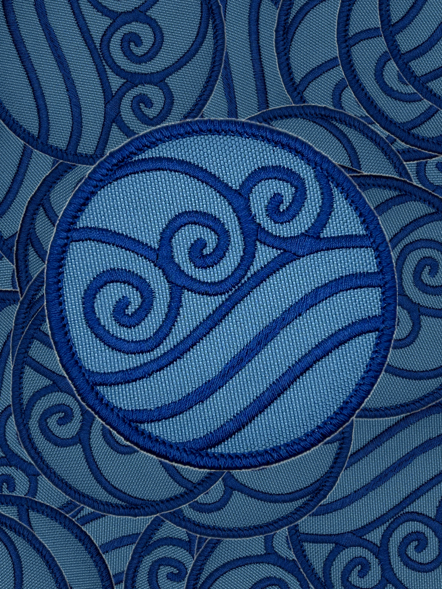 Blue embroidered water bending design on a blue fabric background