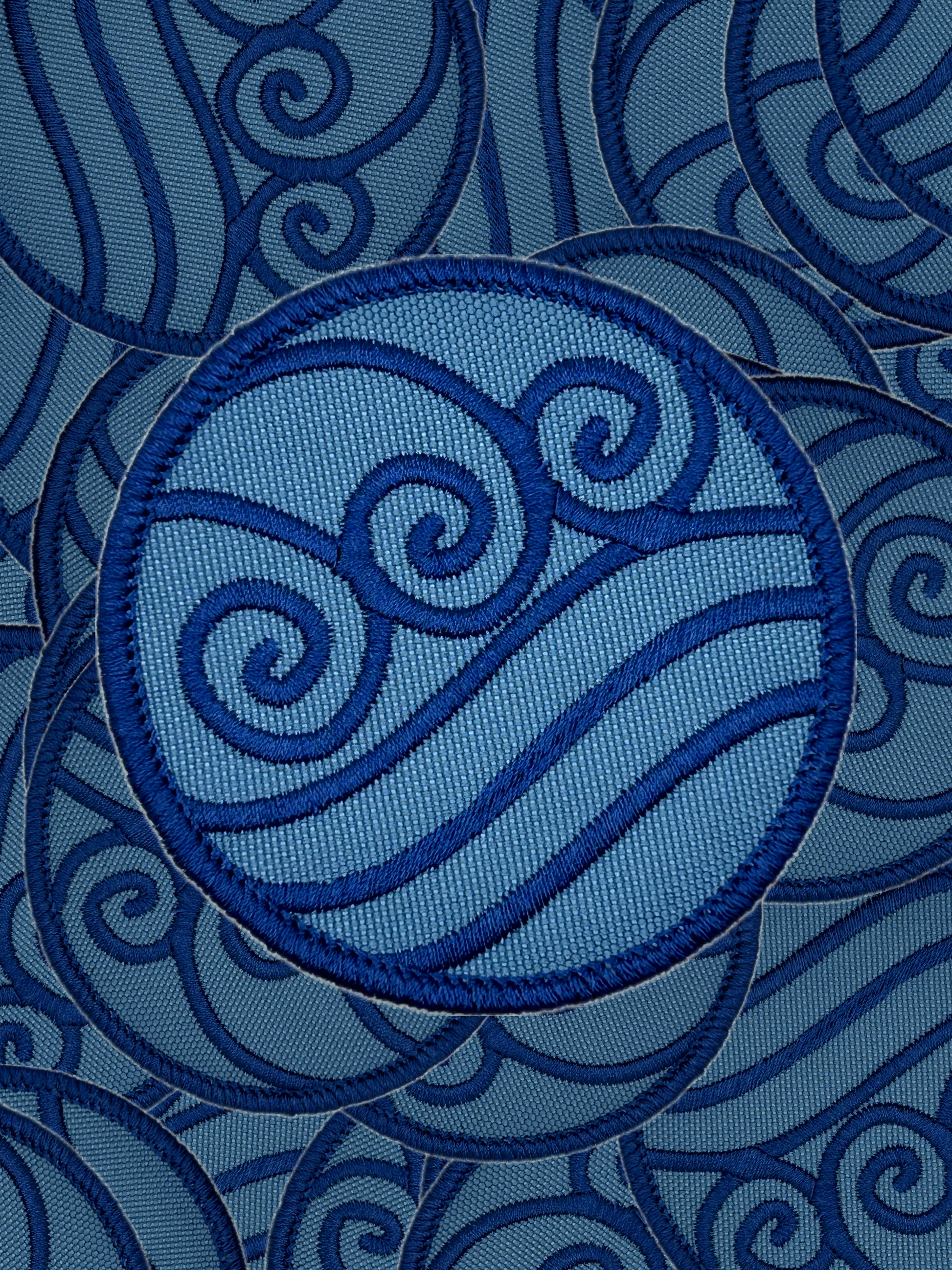 Blue embroidered water bending design on a blue fabric background