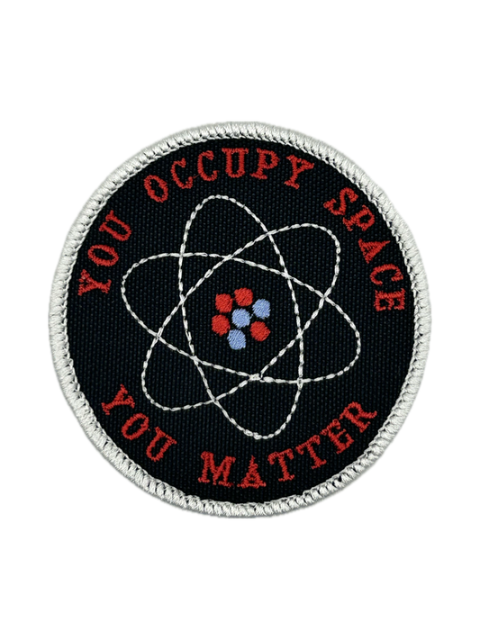 Round patch with atomic symbol and text 'YOU OCCUPY SPACE YOU MATTER' on a black background