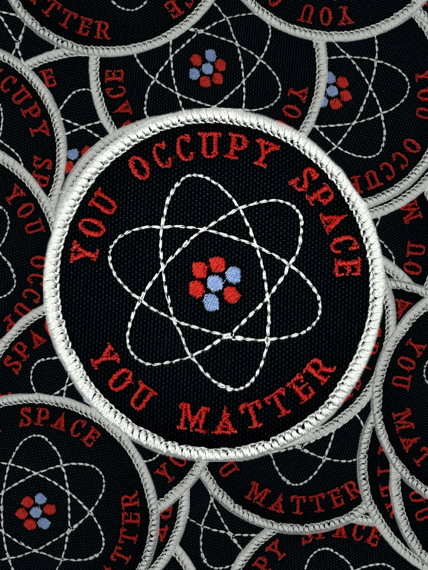 Patch with atomic design and text 'You Occupy Space You Matter' on a black background