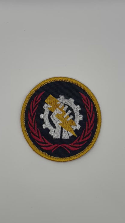 Circular Skitarii patch with a gear and hand design on a black background