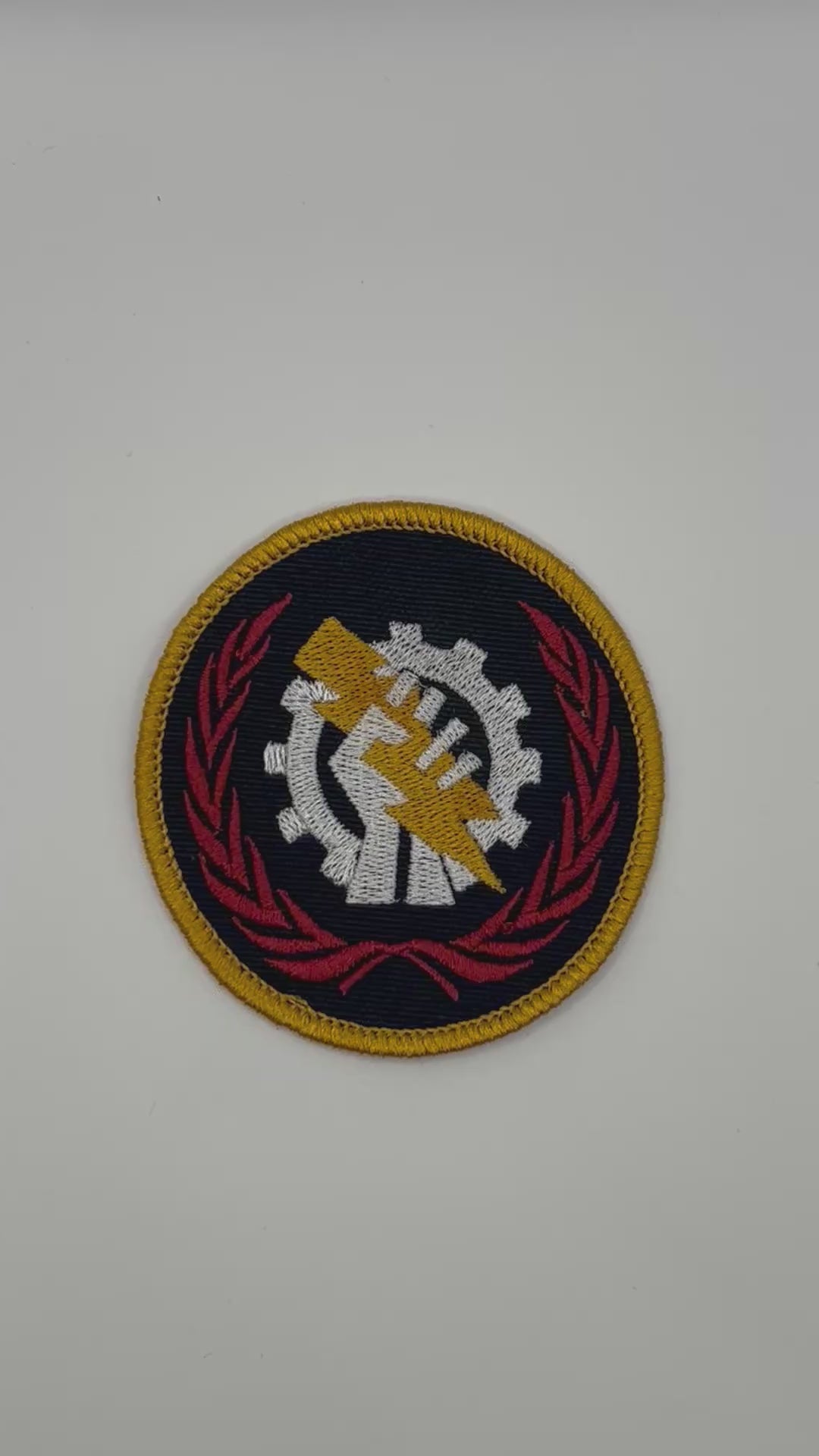 Circular Skitarii patch with a gear and hand design on a black background