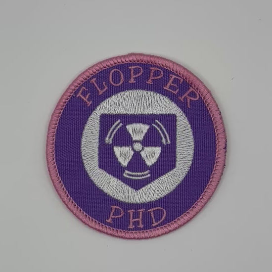 Circular patch with 'FLOPPER PHD' text and a radiation symbol on a white background