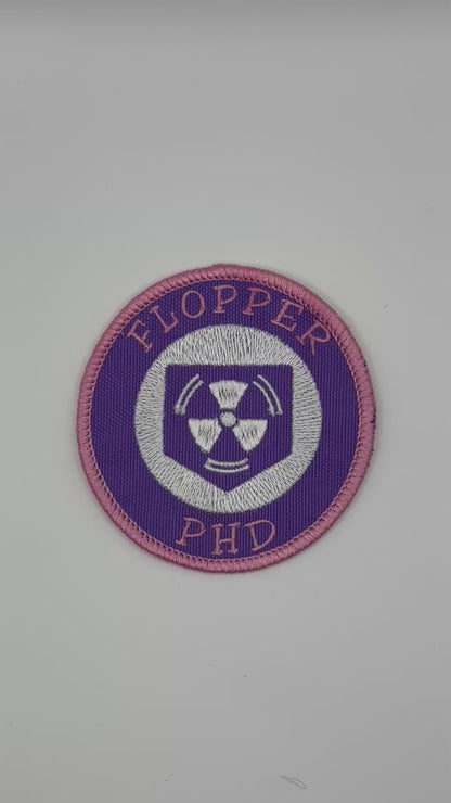 Circular patch with 'FLOPPER PHD' text and a radiation symbol on a white background