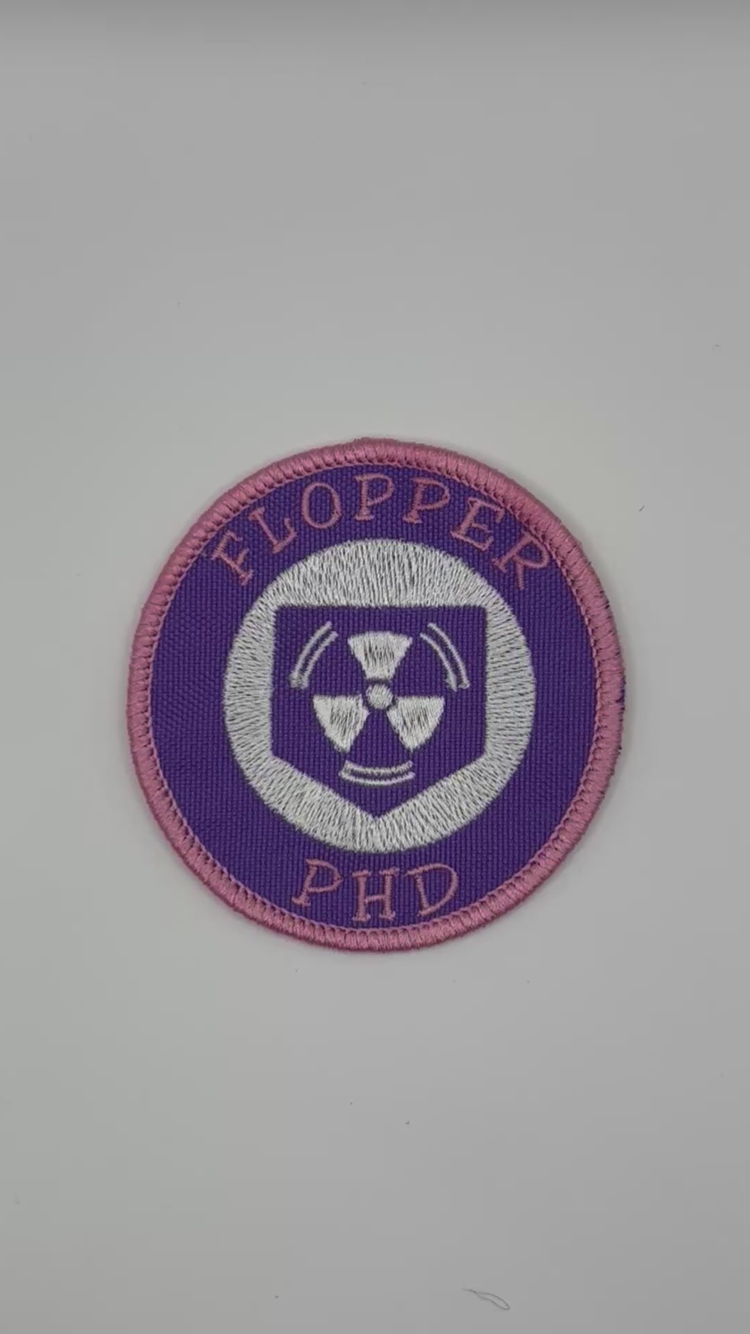 Circular patch with 'FLOPPER PHD' text and a radiation symbol on a white background