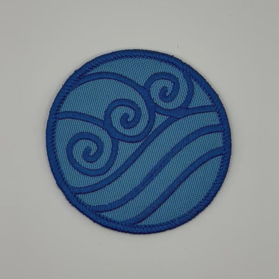 Blue circular waterbending patch with wave design on a white background
