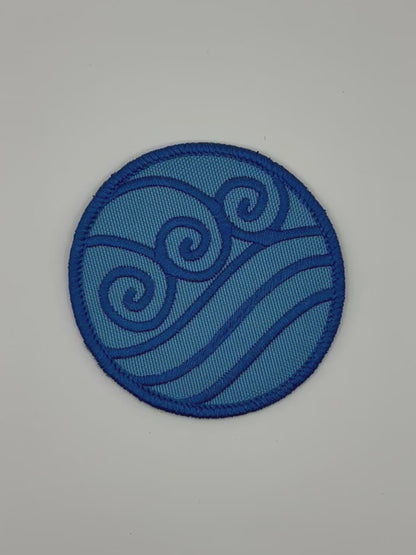 Blue circular waterbending patch with wave design on a white background