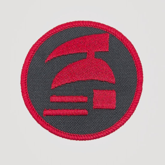 Red and black circular patch with a logo on a white background. Hardcore ironman logo patch.