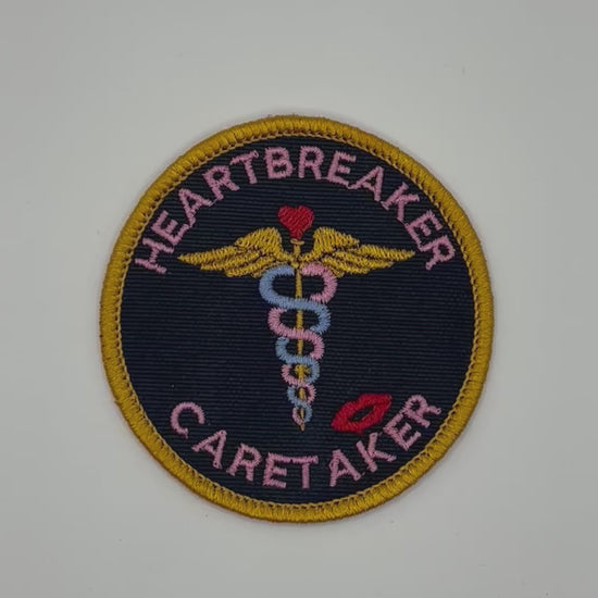 Patch with 'Heartbreaker Caretaker' text and medical symbol on a black background