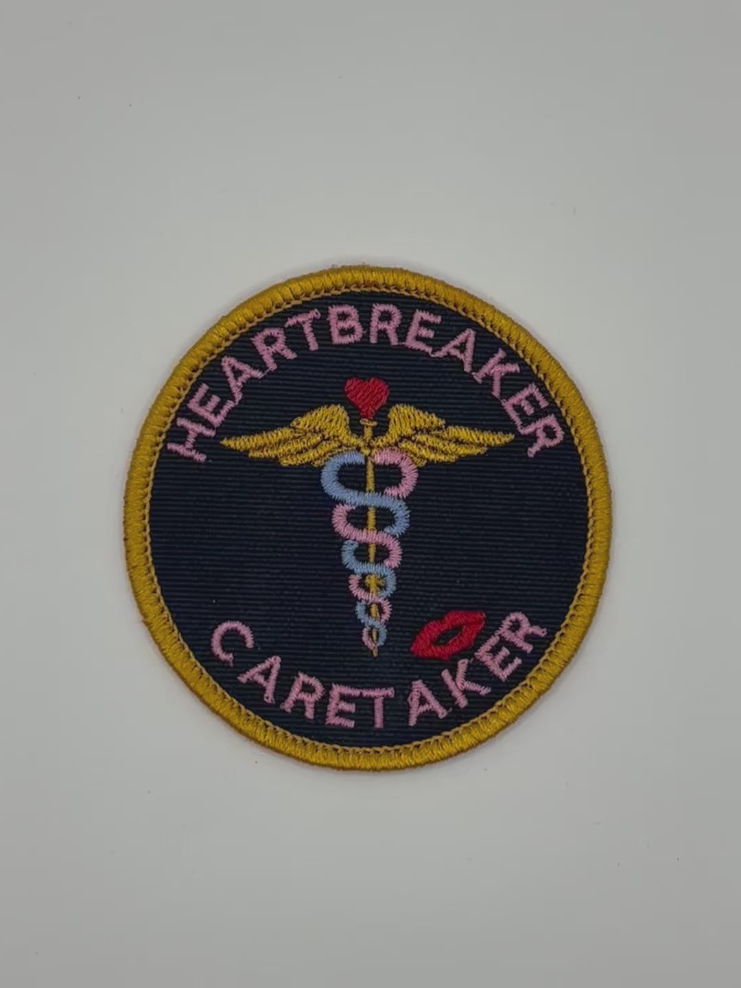 Patch with 'Heartbreaker Caretaker' text and medical symbol on a black background