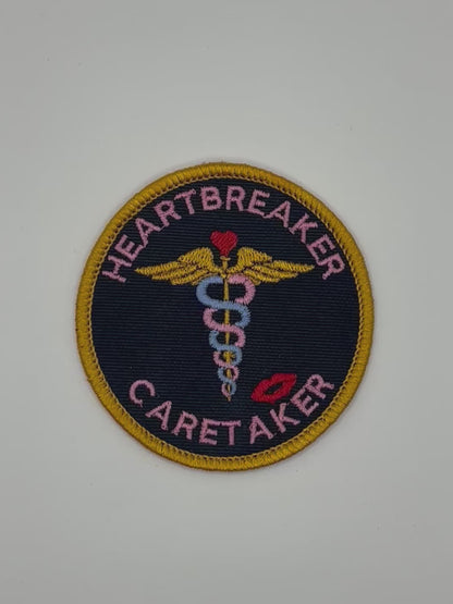 Patch with 'Heartbreaker Caretaker' text and medical symbol on a black background