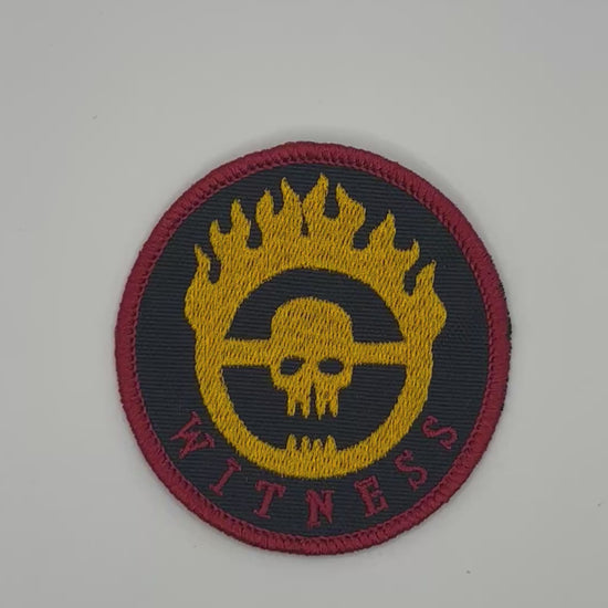 Round patch with skull design and 'Witness' text on a black background